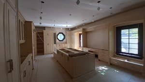 Inside the hallway of a house that is under construction. There are circular pillars and a wooden textured wall