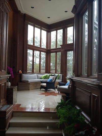interior of a beautiful home with marble floors, mahagony walls, and full-length windows